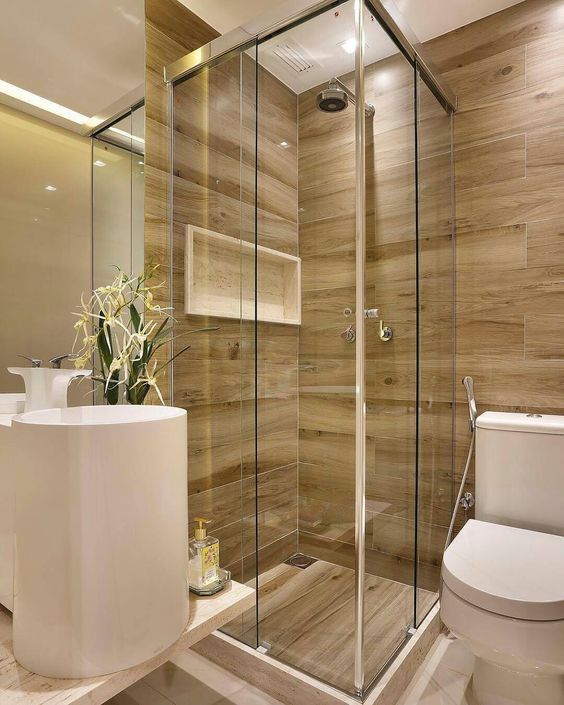 Hình ảnh phòng tắm hiện đại với bồn cầu, bồn rửa bằng sứ màu trắng, buồng tắm kính, tường ốp gỗ