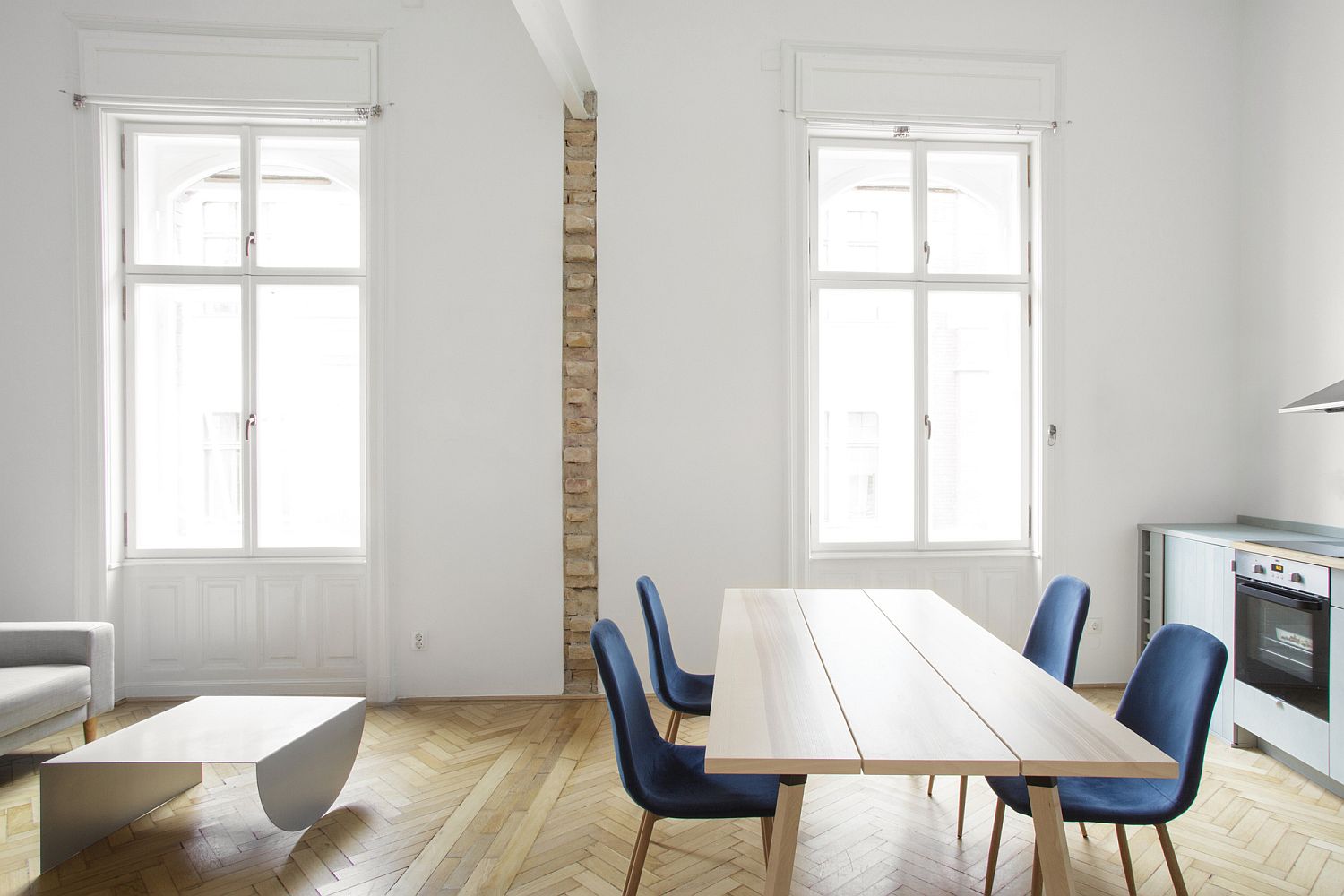 Phòng bếp nổi bật với những chiếc ghế ăn bọc nệm màu xanh dương đậm trở thành điểm nhấn màu sắc nổi bật trong căn hộ có gác lửng.