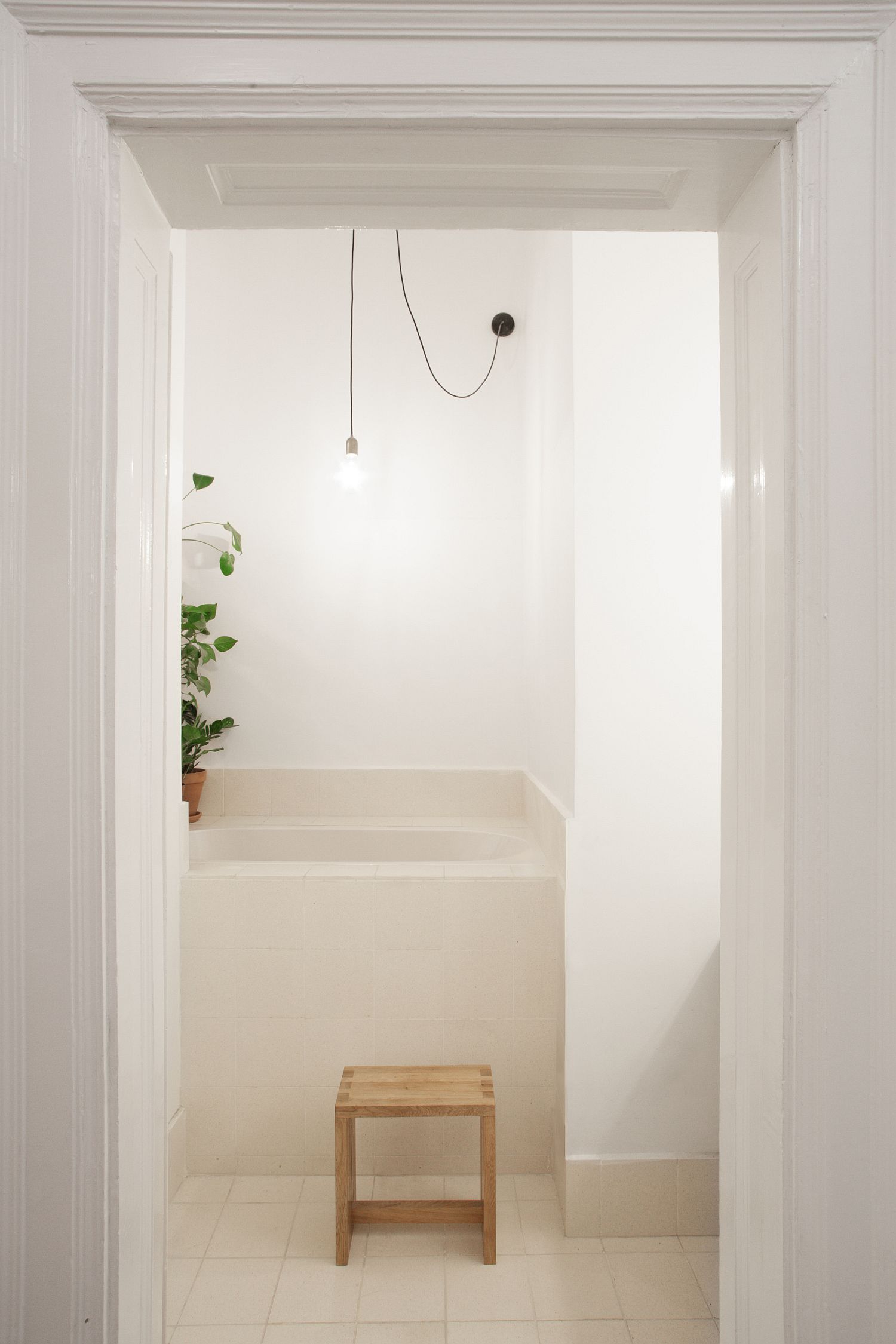 Hình ảnh một góc phòng tắm với ghế gỗ nhỏ, đèn thả mặt dây chuyền