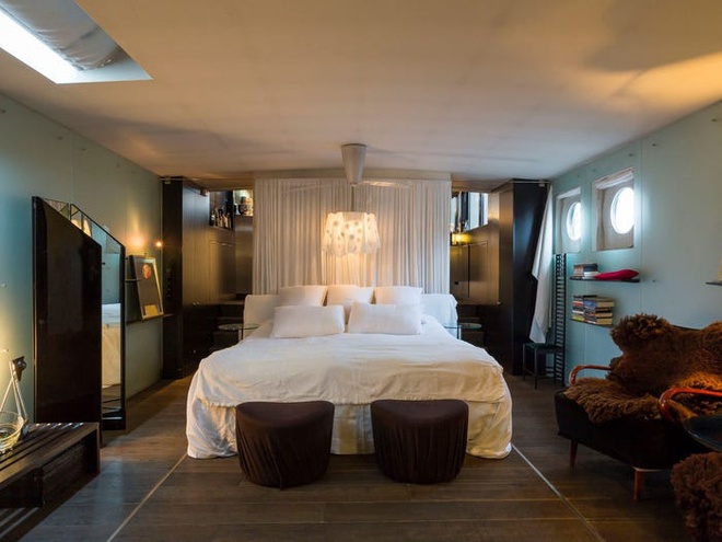 Hình ảnh phòng ngủ với giường lớn, trang trí đầu giường ấn tượng, ghế ngồi thư giãn, tiếp khách