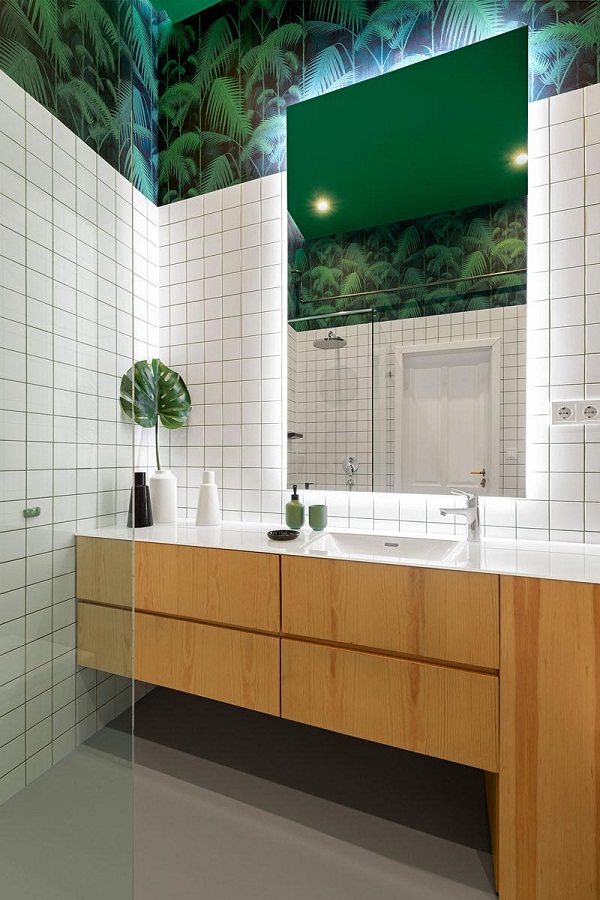 Hình ảnh phòng tắm với giấy dán tường màu xanh, gạch ốp màu trắng, tủ gỗ dưới bồn rửa