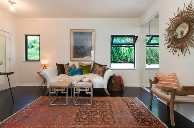 Hình ảnh phòng khách biệt thự với sofa cổ điển, thảm trải màu nóng, gương hình mặt trời, cửa sổ kính