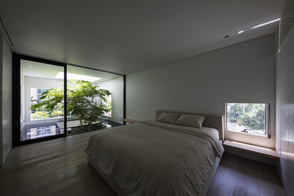 Hình ảnh phòng ngủ có thiết kế tói giản với giường lớn, kệ gỗ 2 bên, ổ cửa kính trong suốt