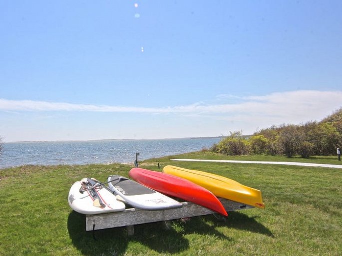 Hình ảnh những chiếc thuyền đua màu sắc nằm trên thảm cỏ xanh mướt, phía trước là biển