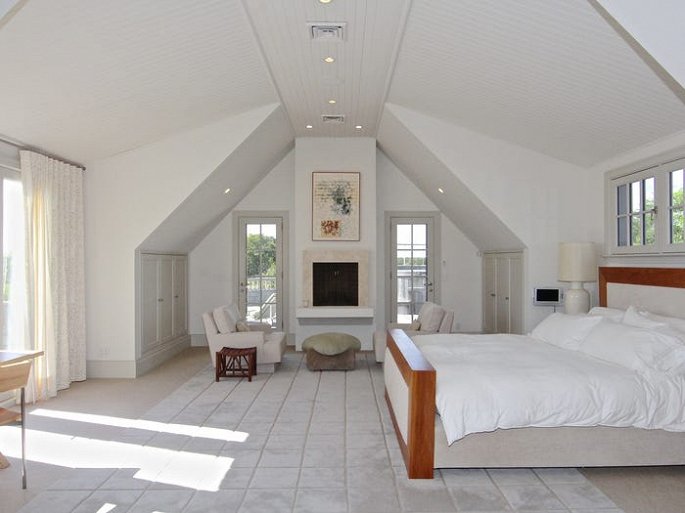 Hình ảnh phòng ngủ chính được thiết kế đơn giản, trần cao và khung cửa kính đón sáng tự nhiên.
