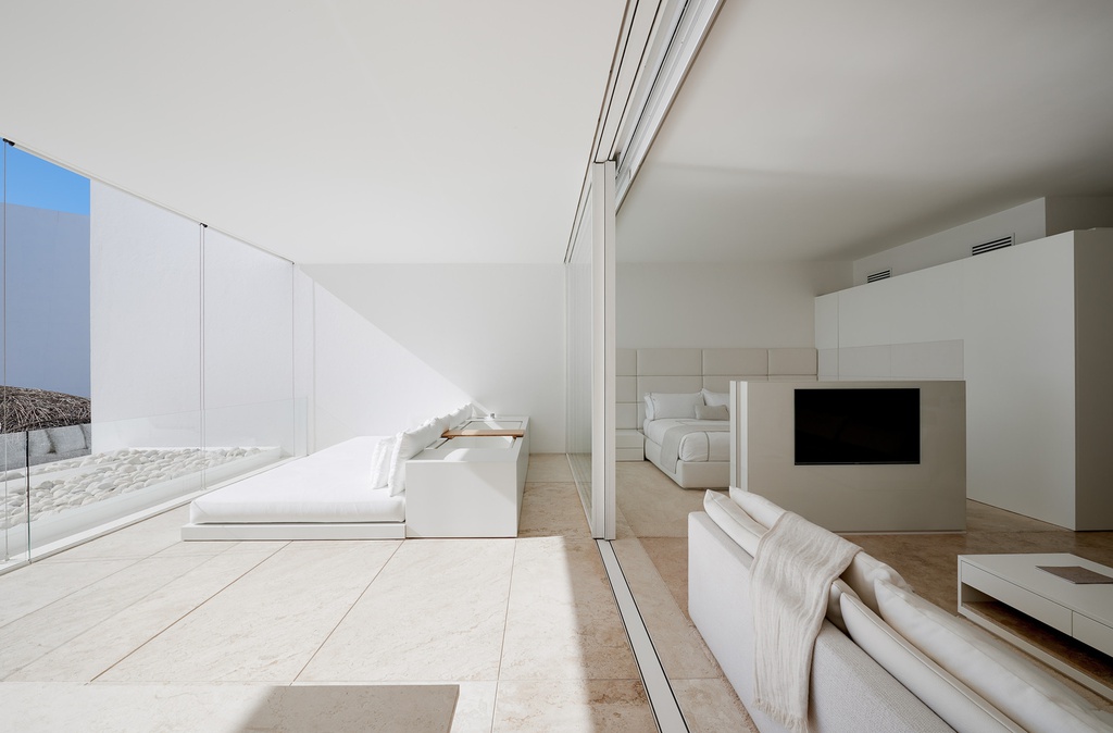Hình ảnh bên trong một phòng condotel với giường, sofa, ghế ngồi thư giãn màu trắng, hướng nhìn ra biển