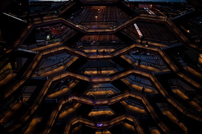 Hình ảnh hệ thống cầu thang bên trong tòa nhà độc đáo khi đêm xuống với ánh đèn vàng lung linh, ấm áp