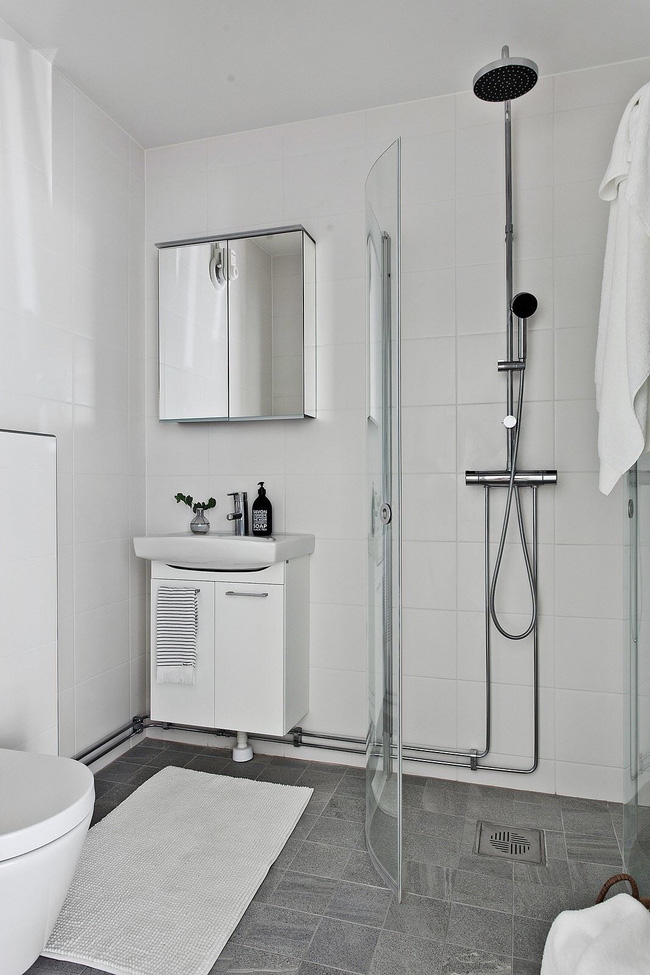 Hình ảnh phòng tắm màu trắng với khu vệ sinh và tắm đứng phân tách qua vách kính trong suốt