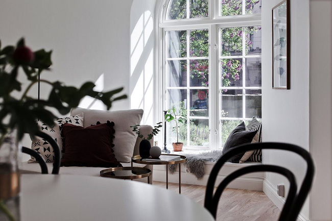 Hình ảnh một góc phòng khách với sofa trắng, cây xanh trang trí, cửa sổ vòm
