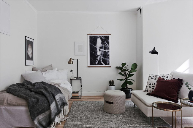 Hình ảnh góc phòng ngủ liền kề phòng khách với sofa trắng, chăn nệm trung tính, chậu cảnh, tranh treo tường