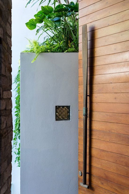 Hình ảnh một góc nhà với tường bê tông, trụ gạch, bồn cây xanh mát