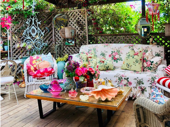 Hình ảnh phòng khách ngoài trời với sofa bọc vải họa tiết hoa lớn, sàn gỗ, phên dậu, họa tiết cầu kỳ
