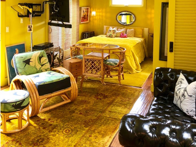 Phòng ngủ chính màu vàng chanh, bàn ghế bằng mây đan, sofa da, gương trang trí đầu giường