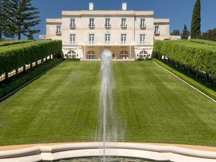 Hình ảnh một góc biệt thự được xây dựng theo phong cách Pháp cổ điển, phía trước là sân vườn xanh mát, hày cây cắt tỉa cầu kỳ