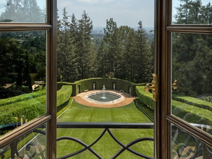 Hình ảnh khu vườn xanh mướt, cắt tỉa đẹp mắt nhìn từ cửa sổ kính