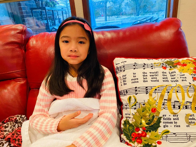 Hình ảnh con gái của nữ ca sĩ Hồng Ngọc ngồi trên sofa màu đỏ