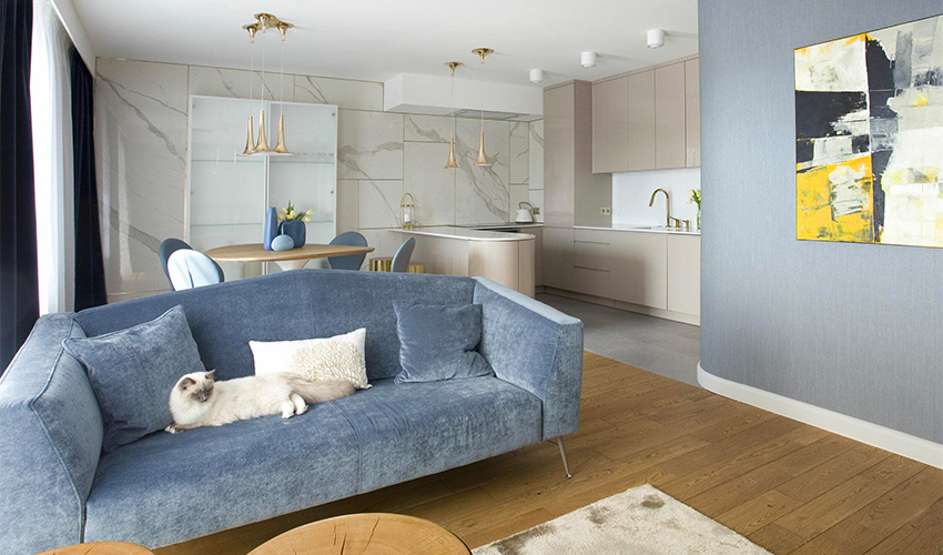 Phòng khách căn hộ phong cách tối giản nổi bật với ghế sofa bọc nhung màu xanh nhẹ nhàng, cạnh đó là khu vực bếp nấu, bàn ăn