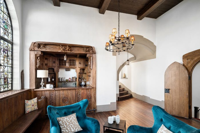 Hình ảnh không gian phòng khách ấn tượng với cửa sổ kính màu, trần nhà cao nội thất gỗ chạm khắc tinh xảo, ghế ngồi bọc nệm màu xanh dương
