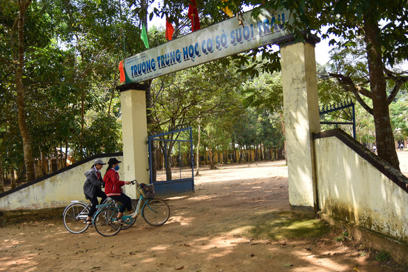 Hình ảnh cận cảnh công trường Trường THCS Suối Trầu huyện Long Thành, Đồng Nai với nhiều cây cối bao quanh, hai em học sinh đạp xe