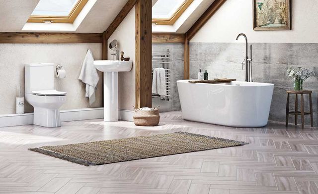 Hình ảnh phòng tắm tầng áp mái với cửa sổ trần, bồn tắm lớn màu trắng sứ, dầm gỗ, thảm trải màu trung tính