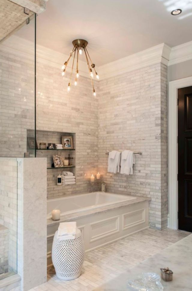 Hình ảnh phòng tắm mang hơi hướng cổ điển với tường ốp gạch thẻ màu xám, đèn chiếu sáng màu vàng mờ ảo, bồn tắm hình vuông