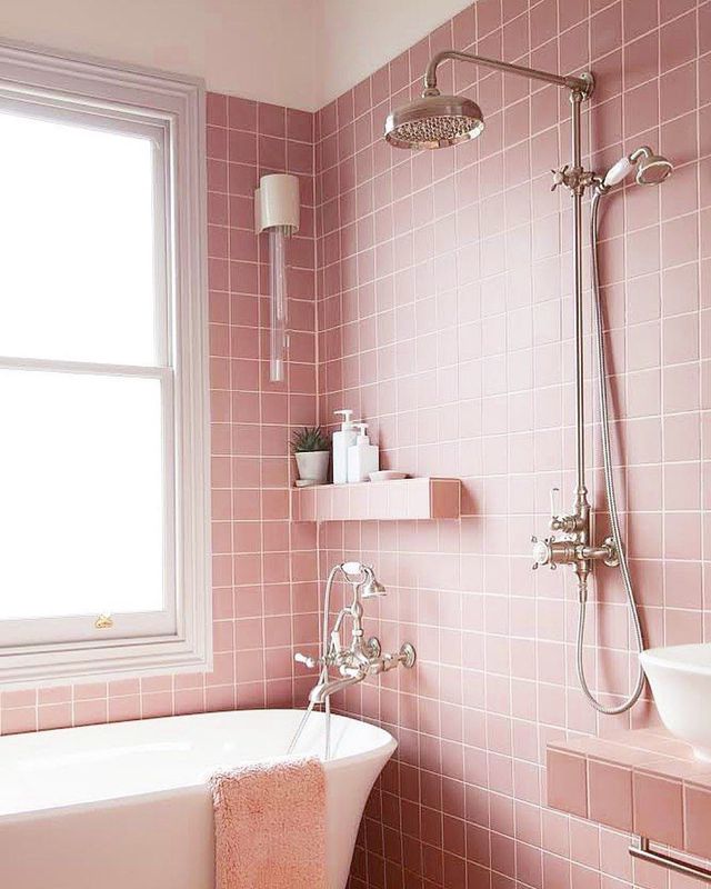 Hình ảnh phòng tắm ngọt ngào với tường ốp gạch hồng, vòi sen đứng, bồn tắm lớn, kệ góc đặt vật dụng cá nhân, chậu cảnh nhỏ xinh