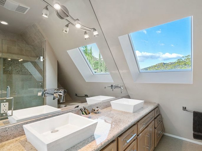 Hình ảnh cận cảnh khu vực bồn rửa đôi trong phòng tắm, phía đưới là tủ gỗ, cửa sổ kính, đèn trang trí
