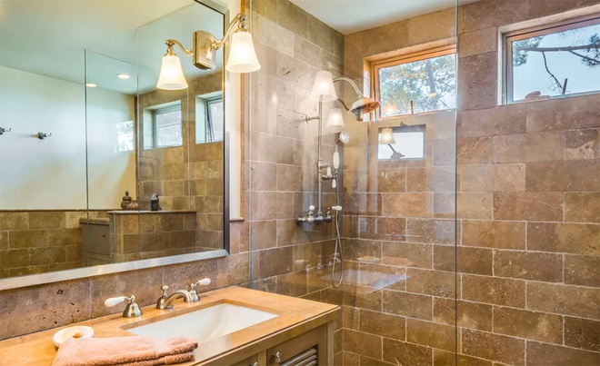 Hình ảnh phòng tắm được ốp gạch màu vàng be ấm áp, trang thiết bị hiện đại, đèn chiếu sáng, vách kính