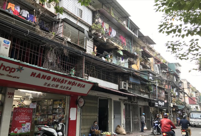 Hình ảnh cận cảnh mặt tiền một khu chung cư cũ tại Hà Nội đã xuống cấp với chuồng cọp dày đặc, hàng quán nhếch nhác