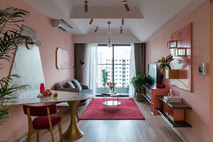 Toàn cảnh phòng khách liền kề bàn ăn với tông màu hồng chủ đạo cho tường, sofa, cây xanh trang trí