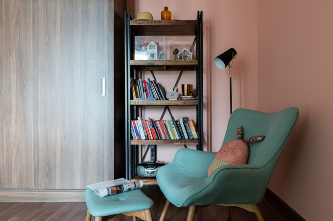 Hình ảnh một góc đọc sách, thư giãn trong phòng ngủ với ghế màu xanh ngọc lam, kệ sắt, đèn sàn 