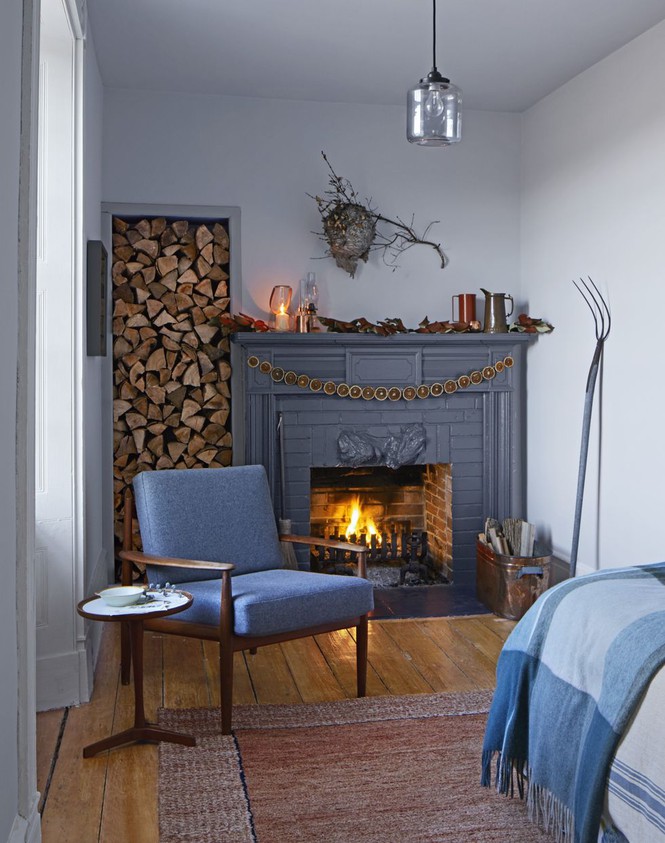 Hình ảnh góc thư giãn ấm áp với lò sưởi, ghế sofa màu xanh dương, phụ kiện trang trí