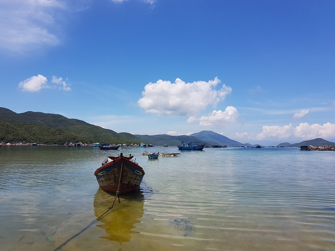 Hình ảnh một góc vịnh Vân Phong với nhiều thuyền bè, xa xa là những dãy núi trùng điệp