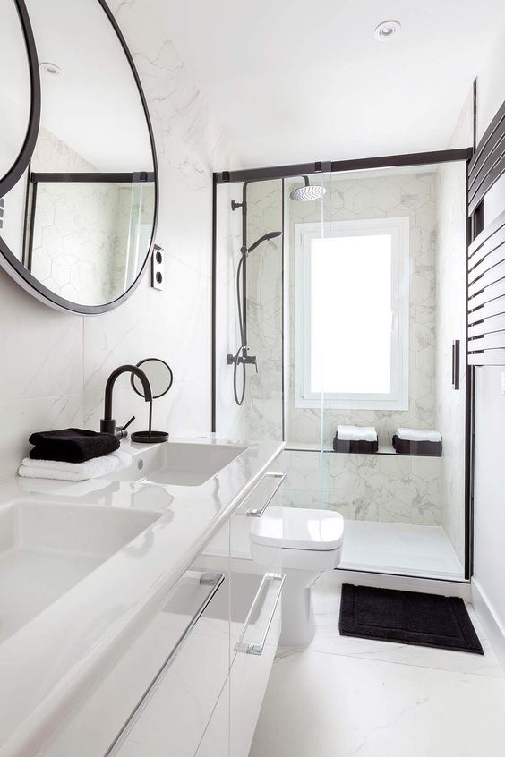 Hình ảnh phòng tắm màu trắng chủ đạo, bồn rửa đôi, gương tròn, vách kính