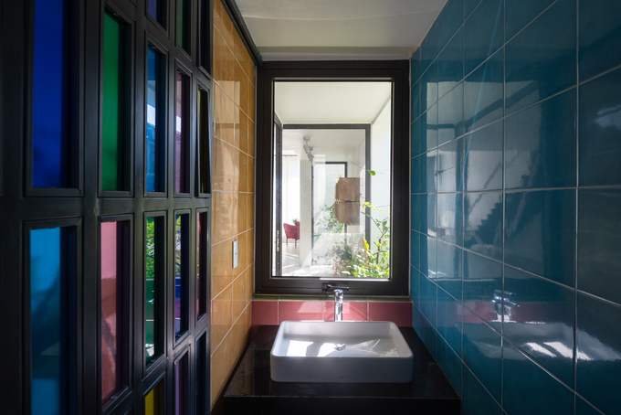 Hình ảnh cận cảnh một góc phòng tắm ấn tượng với tường ốp đá xanh dương, cửa kính màu rực rỡ