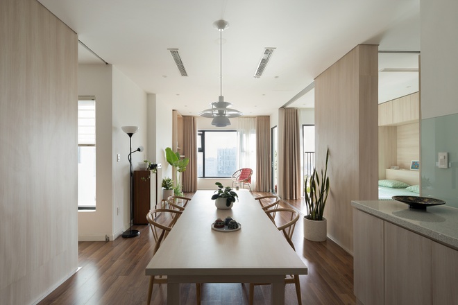 Hình ảnh không gian bên trong căn hộ 80m2 với bàn ăn bằng gỗ hình chữ nhật, sàn gỗ, cây xanh trang trí