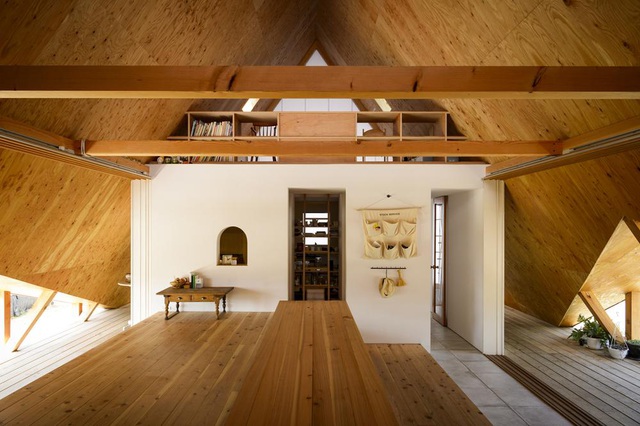 Hình ảnh không gian bên trong ngôi nhà với sàn lát gỗ, tường trắng, cửa sổ tam giác lớn nhỏ khác nhau