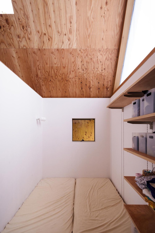 Hình ảnh một phòng ngủ nhỏ gọn màu trắng, trần ốp gỗ, tủ lưu trữ bên cạnh giường