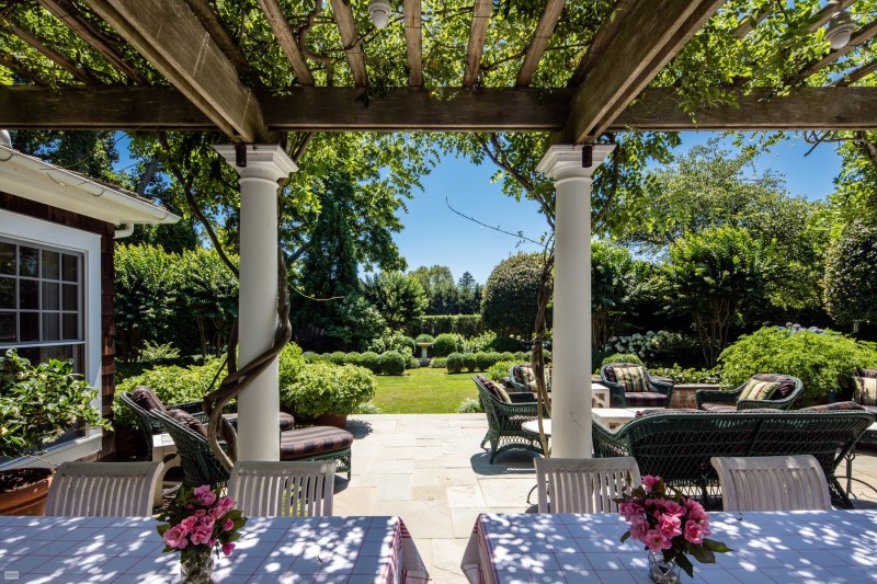 Hình ảnh không gian thư giãn ngoài sân vườn với nhiều bàn ghế trải khăn màu trắng, phía trên đặt bình hoa màu hồng