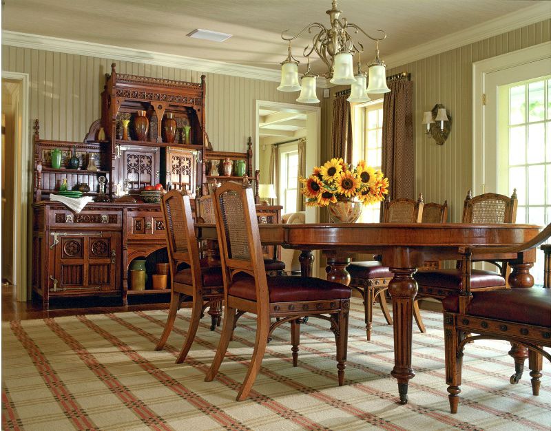 Hình ảnh toàn cảnh phòng ăn biệt thự với bàn tròn lớn, tủ gỗ chạm khắc cầu kỳ, lọ hoa hướng dương trên bàn