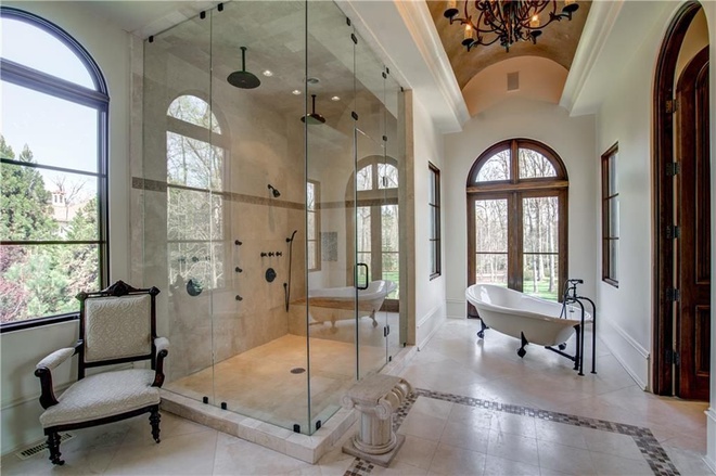 Hình ảnh phòng tắm sang trọng với tông màu trắng sáng chủ đạo, bồn tắm nằm, vách kính trong suốt, cửa sổ vòm