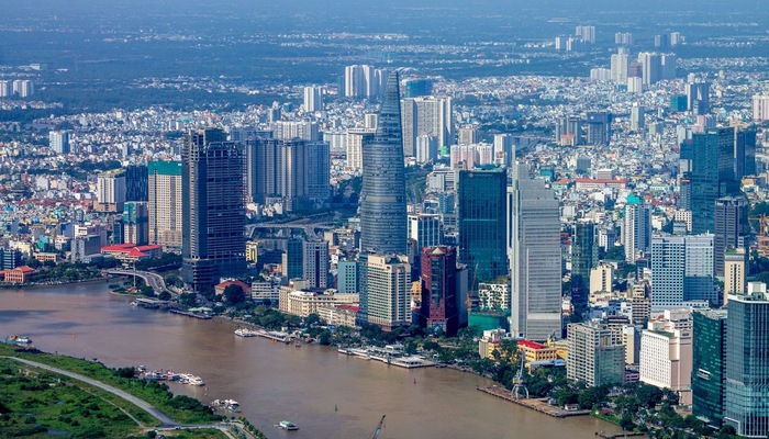 Hình ảnh một góc thành phố sầm uất nhìn từ trên cao với những tòa cao ốc hiện đại, xen kẽ khu dân cư thấp tầng, cây xanh, sông hồ