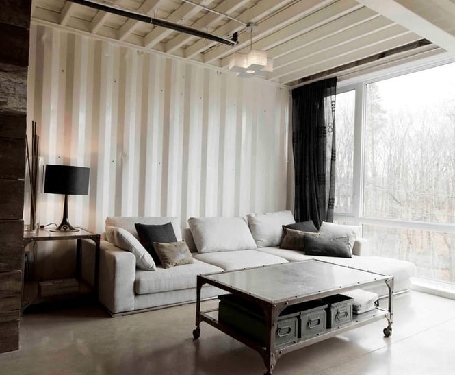 Hình ảnh phòng khách nhà container với sofa trắng cùng tông với tường, trần, bàn trà sắt, cửa sổ kính trong suốt