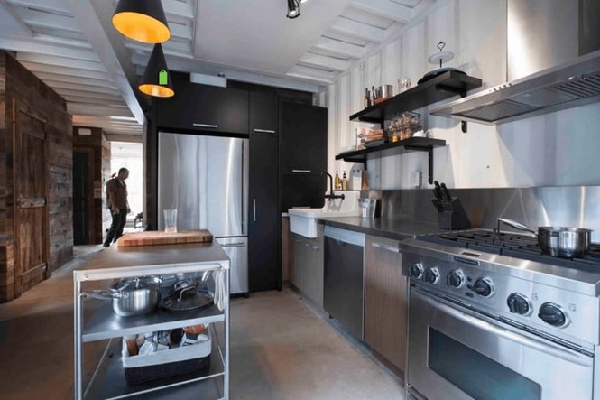 Hình ảnh một phòng bếp với đầy đủ trang thiết bị tông màu xám kim loại, đèn trang trí ấm áp