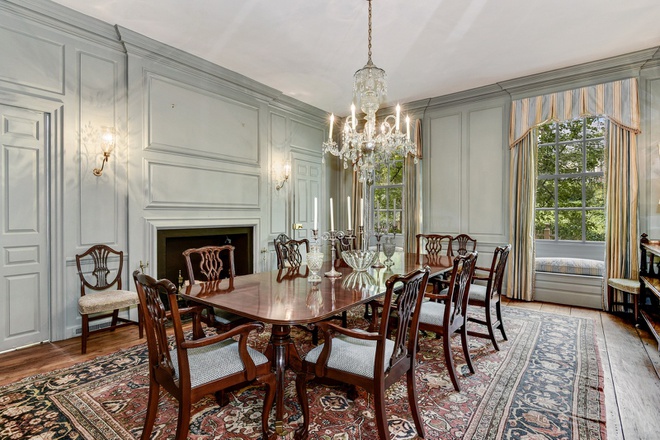 Hình ảnh một phòng ăn cổ điển với trần, tường màu trắng, bàn ghế gỗ chạm khắc tinh tế, đèn chùm trang trí