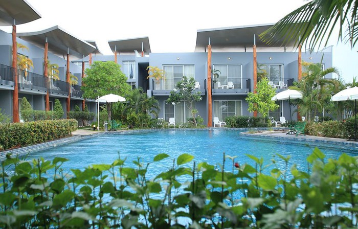 Hình ảnh cận cảnh khuôn viên bể bơi trong khách sạn với cây cối xanh mát bao quanh.