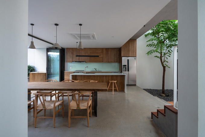 Hình ảnh phòng bếp ăn với tủ, bàn ghế bằng gỗ, đèn thả trần, bồn cây xanh