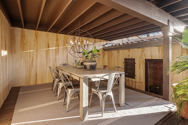Hình ảnh ngay dưới hiên nhà là bàn ăn bằng gỗ xám kết hợp tinh tế với bộ ghế cùng tông màu.