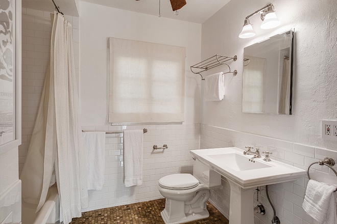 Hình ảnh một phòng tắm hiện đại với tường, trần và nội thất cùng màu trắng, gạch lát màu vàng nâu
