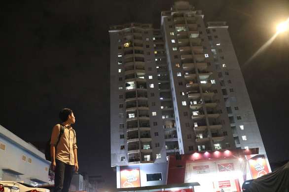 Hình ảnh một người đàn ông trẻ tuổi đang hướng nhìn lên tòa chung cư cao tầng đã bàn giao cho cư dân vào ở